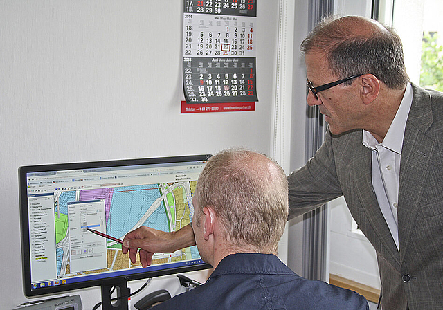 Orientierung per Bildschirm: Gemeindepräsident Giorgio Lüthi (rechts) und der vonseiten Bauverwaltung zuständige Projektleiter Harald Puchrucker bei der Arbeit mit dem Münchensteiner GIS.  Foto: ZVG