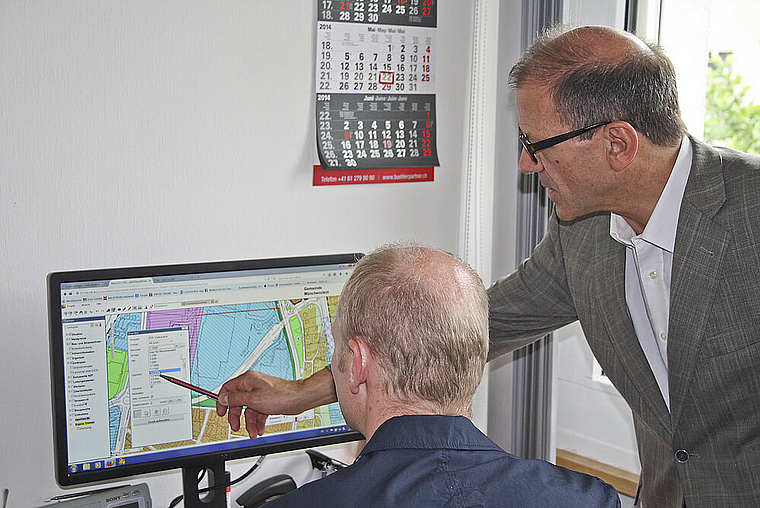 Orientierung per Bildschirm: Gemeindepräsident Giorgio Lüthi (rechts) und der vonseiten Bauverwaltung zuständige Projektleiter Harald Puchrucker bei der Arbeit mit dem Münchensteiner GIS.  Foto: ZVG