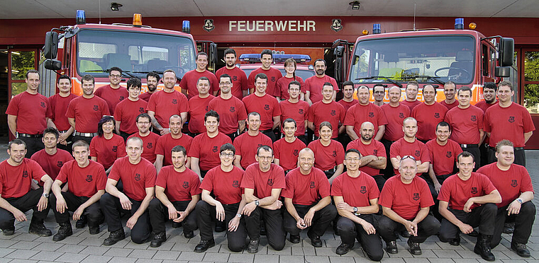 Mannschaftsfoto: Die Münchensteiner Feuerwehr im «Arbeitstenue», im Hintergrund die Einsatzfahrzeuge.  Foto: ZVG