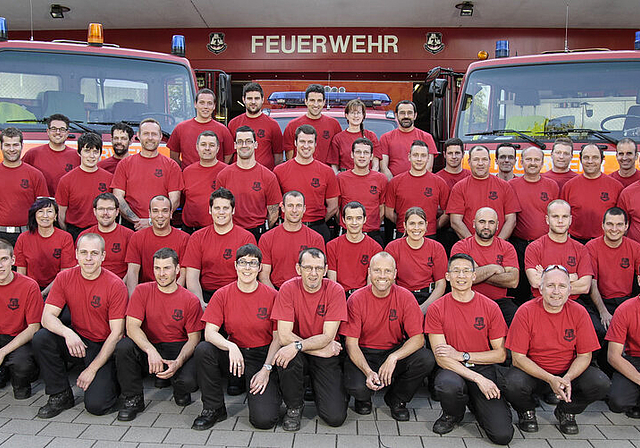 Mannschaftsfoto: Die Münchensteiner Feuerwehr im «Arbeitstenue», im Hintergrund die Einsatzfahrzeuge.  Foto: ZVG