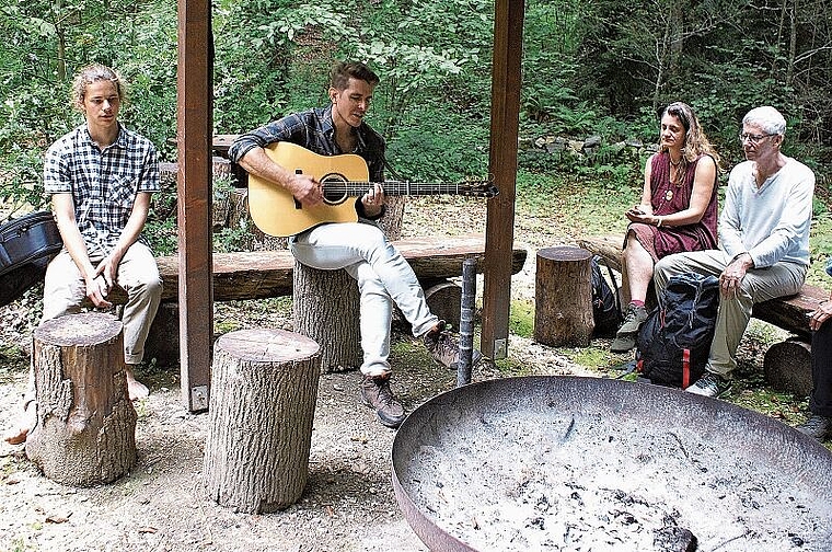 Wanderkonzert mit einzigartigen Stationen: Flavian Graber (2. v. l.) mit den Teilnehmerinnen und Teilnehmern des Wanderkonzerts an der Feuerstelle. Foto: Jürg Jeanloz