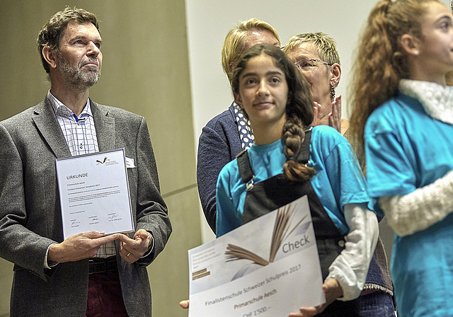 Eine Urkunde und 1500 Franken: Niggi Thurnherr, Schulleiter der Primarstufe Aesch, und eine Schülerin mit den verdienten «Trophäen» anlässlich der Verleihung des Schweizer Schulpreises am 13. Dezember in Bern.  Foto: ZVG/Adrian Moser