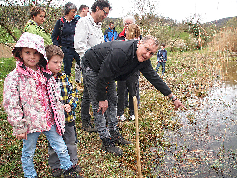 Praktischer Naturschutz: Gemeinderat Paul Svoboda beim vorderen Klusweiher. Er zeigt den Besuchern den Laich der Amphibien. Foto: Tobias Gfeller