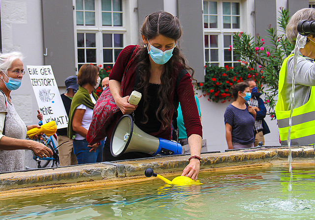 Symbolischer Akt: Jennifer McGowan, Sprecherin der Initiative Natur- und Kulturraum Dornach-Arlesheim, füllt ihre Giesskanne am Brunnen des Domplatzes.  Foto: Tobias Gfeller