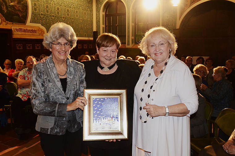 Preisübergabe: Therese Mathys (l.), Mitglied der Kulturkommission der Bürgergemeinde, übergibt den «Münggestei» in Form eines Gemäldes von Ivan Grill an Meta Zweifel (Mitte), daneben Laudatorin Julia Onken.  Foto: Heiner Leuthardt