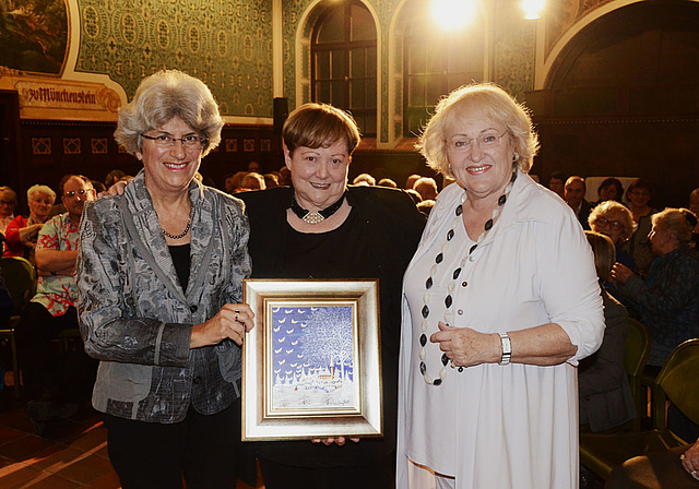 Preisübergabe: Therese Mathys (l.), Mitglied der Kulturkommission der Bürgergemeinde, übergibt den «Münggestei» in Form eines Gemäldes von Ivan Grill an Meta Zweifel (Mitte), daneben Laudatorin Julia Onken.  Foto: Heiner Leuthardt