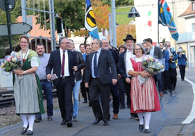 <em>Offizieller Einmarsch: </em>Regierungsrat Remo Ankli (l.) im Gespräch mit OK-Präsident Thomas E. Ruppli, flankiert von den Ehrendamen des Bäuerinnen- und Landfrauenvereins Leimental, gefolgt vom OK, von den Gästen und musikalisch begleitet vo