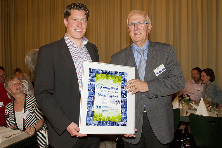 Abschiedsgeschenk: Michael Dreier, frischgebackener Präsident des Vereins Gewerbe und Industrie Aesch, übergibt dem frischgebackenen Ehrenpräsidenten Roland Hohl eine Rebpatenschaft mit dem passenden Namen «Clos du Roland».  Foto: ZVG/Claudia Sc