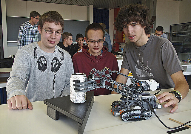 Greifroboter an der Arbeit: v. l. Martin Saladin, Philipp Neth, Michel Vögtli. Die drei bauten die Maschine, die den Linien entlang fährt und am Ende eine mit Alu eingepackte Colabüchse greift und hievt.  Foto: Tobias Gfeller