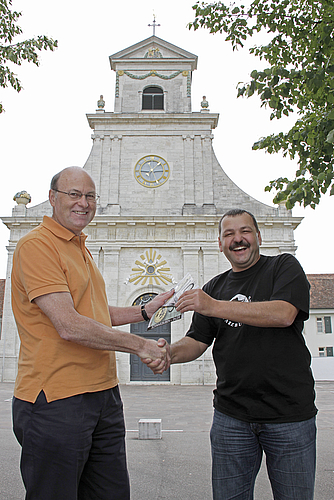 Vor prägender Kulisse: Martin Vogel (r.) übergibt Paul Schönenberger die neue, gesunde Währung vor der Klosterkirche Mariastein. Fotos: Martin Staub
