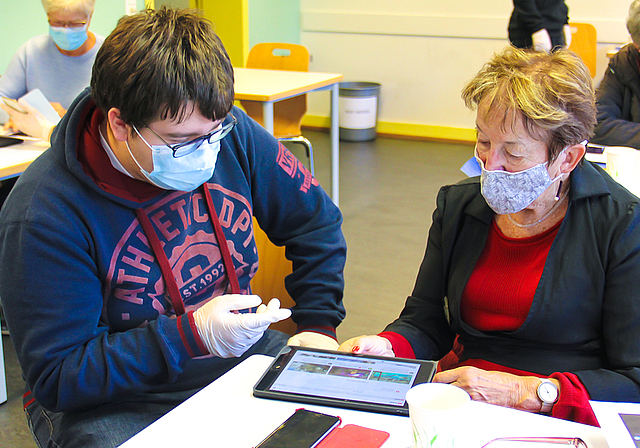 Neue Technologie kennen lernen: Ein Schüler bringt der Seniorin die SBB-App näher.  Foto: Tobias Gfeller