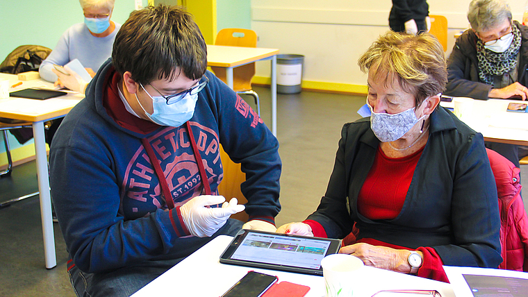 Neue Technologie kennen lernen: Ein Schüler bringt der Seniorin die SBB-App näher.  Foto: Tobias Gfeller