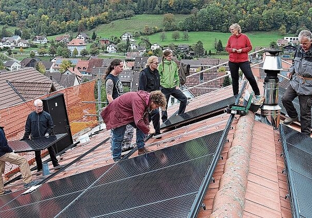 Montieren der Photovoltaikanlage: Florin Schaffner, Projektleiter von der Energiewendegenossenschaft Basel (Mitte, rote Jacke), die Bauherrschaft Susanne Koch und Martin Hauser (rechts) und Mithelfende. Foto: Gaby Walther