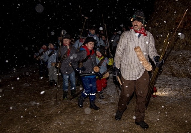 Aufmarsch im Schnee: Konrad Gschwind mit Kinderschar umrundet das aufgeschichtete Fasnachtsfeuer. Foto: Martin Staub