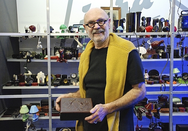 Bakelit wird museal: Jürg Josef Zimmermann präsentiert eine Bakelitdose mit kunstvollem Relief. Im Hintergrund: Vitrine mit Bakelit-Lampen.  Foto: Thomas Brunnschweiler