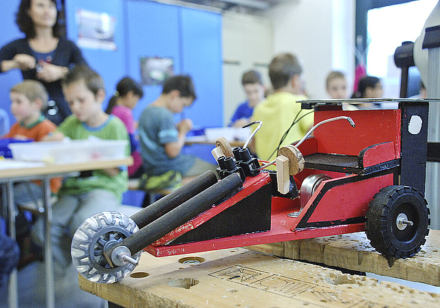 Ferienpass-Werkstatt: Im Vordergrund ein fertiger Prototyp eines Solar-Trikes, im Hintergrund eifrig arbeitende Kinder. Foto: Brunnschweiler