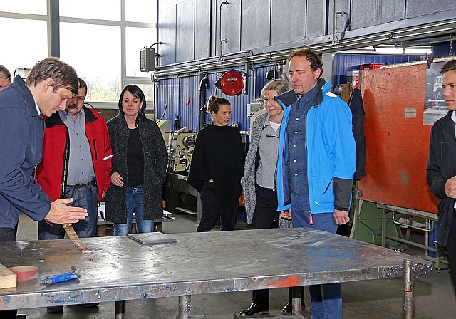 <em>Präzision: </em>Gregor Schreier (l.) und Lukas Schreier (2.v.r.) erläutern der Regierungsrätin Brigit Wyss (3.v.r.) und anderen Gästen, wie selbst in einer hochmodernen Werkstatt manche Teile von Hand ausgestanzt werden.Foto: GINI Minonzio