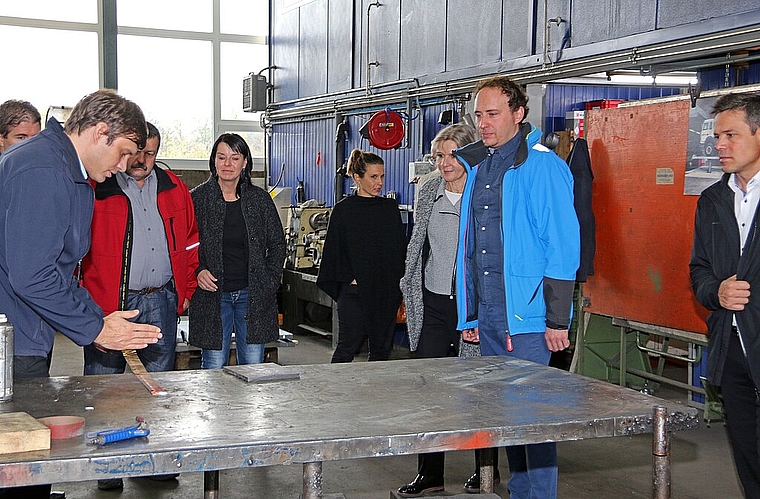 <em>Präzision: </em>Gregor Schreier (l.) und Lukas Schreier (2.v.r.) erläutern der Regierungsrätin Brigit Wyss (3.v.r.) und anderen Gästen, wie selbst in einer hochmodernen Werkstatt manche Teile von Hand ausgestanzt werden.Foto: GINI Minonzio