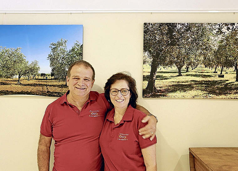 Besitzen benachbarte Olivenplantagen: Francesco Augello und Francesca Augello jeweils vor dem Bild ihrer eigenen Olivenplantage. Foto: Simone Pürro