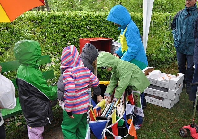 Trotz Regen eifrig dabei: Junge Leser befüllen einen Buchkasten des neu eröffneten Kinderbuchwegs in Münchenstein.
