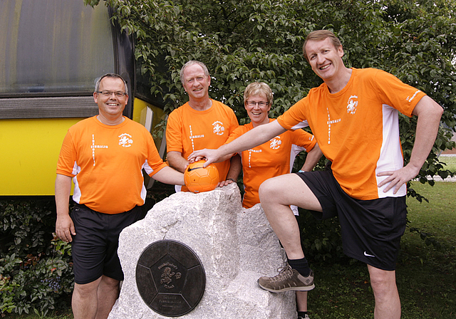 Ein Denkmal für die Aescher Fussballschule: Erich Mohn (Chef Trainer), Max Hunziker (Chef auf Platz), Heidi Gerster (Chef Verpflegung) und Christoph Heller (Chef Organisation) freuen sich über die in Stein gehauene Würdigung.  Foto: Lukas Hausendo