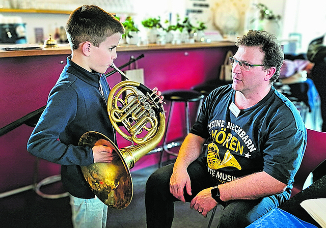 Ob es wohl das Waldhorn wird?: Ben bläst zum ersten Mal ins Instrument und lässt sich dabei von Musiklehrer José Martin Blanco instruieren. Foto: Melanie Brêchet