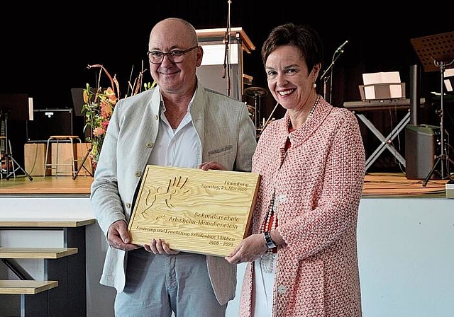 Erinnerung an den Umbau: Bau- und Umweltschutzdirektor Isaac Reber übergibt Bildungsdirektorin Monica Gschwind eine Holztafel zur Einweihung des Lärchen-Schulhauses. Fotos: Jeannette Weingartner
