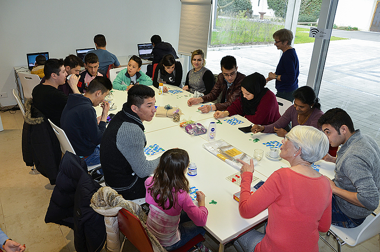 Willkommene Abwechslung im monotonen Flüchtlingsalltag: Im Pfarrhof St. Josef spielen Männer, Frauen und Kinder zusammen mit freiwilligen Helferinnen und Helfern einen Lottomatch.  Foto: Thomas Kramer