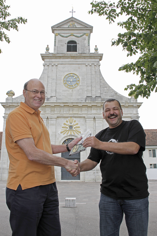 Vor prägender Kulisse: Martin Vogel (r.) übergibt Paul Schönenberger die neue, gesunde Währung vor der Klosterkirche Mariastein. Fotos: Martin Staub
